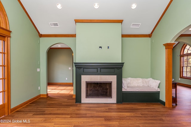 unfurnished living room featuring ornate columns, ornamental molding, and hardwood / wood-style floors