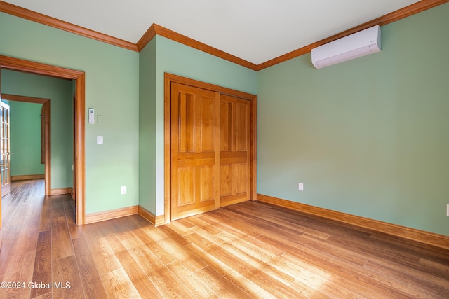 unfurnished bedroom with light wood-type flooring, ornamental molding, and an AC wall unit