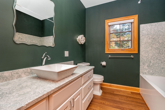 bathroom featuring wood-type flooring, a tub to relax in, vanity, and toilet