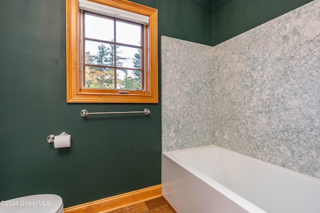 bathroom featuring a bathtub, hardwood / wood-style flooring, and toilet