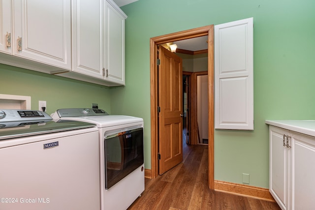 clothes washing area with ornamental molding, washer and dryer, dark hardwood / wood-style floors, and cabinets