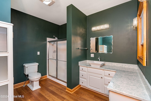 bathroom with wood-type flooring, a shower with shower door, vanity, and toilet