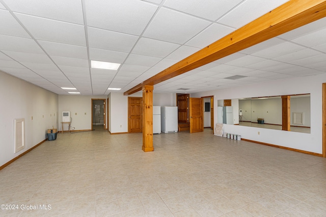 basement with white refrigerator and a drop ceiling