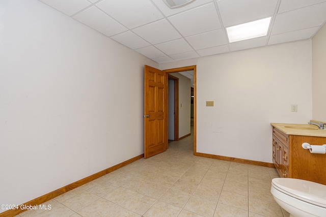 bathroom featuring vanity, a drop ceiling, toilet, and tile patterned floors