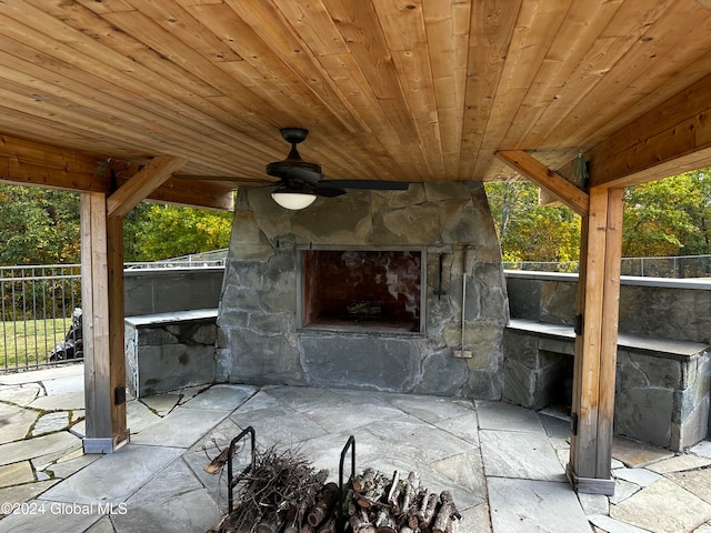 view of patio featuring an outdoor stone fireplace and ceiling fan