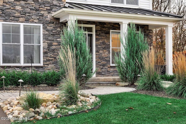 doorway to property featuring a standing seam roof, stone siding, and metal roof