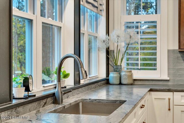 details featuring white cabinets, dark stone counters, and a sink