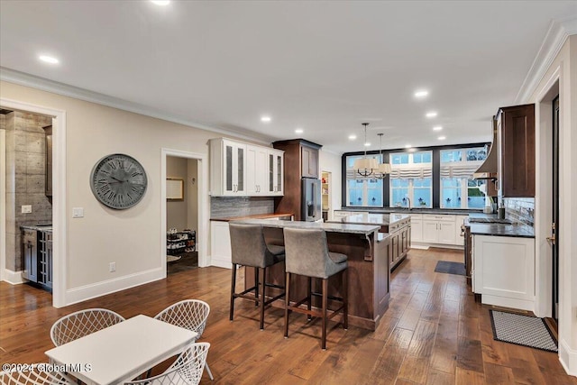 kitchen featuring dark wood finished floors, stainless steel refrigerator with ice dispenser, backsplash, and a kitchen island