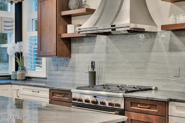 kitchen featuring ventilation hood, open shelves, dark stone counters, and gas stove