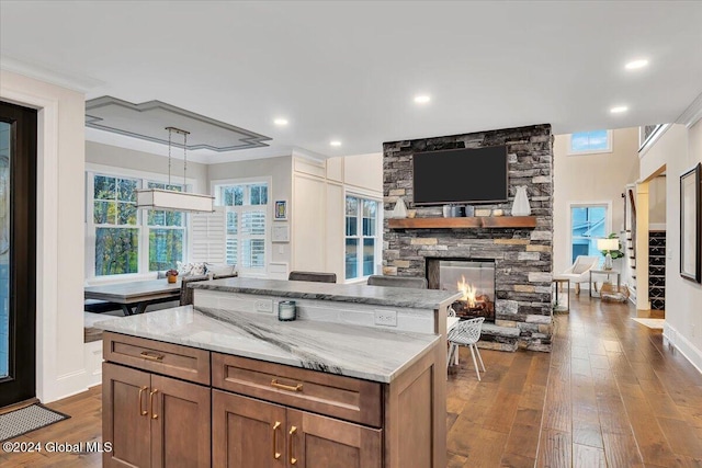 kitchen featuring a stone fireplace, dark wood-type flooring, and light stone countertops