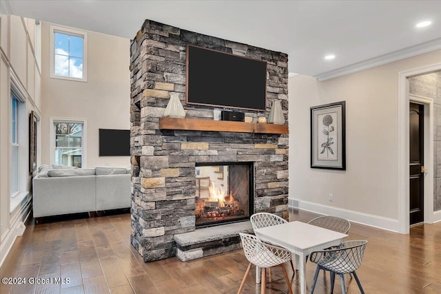 living area with wood finished floors, recessed lighting, a fireplace, crown molding, and baseboards