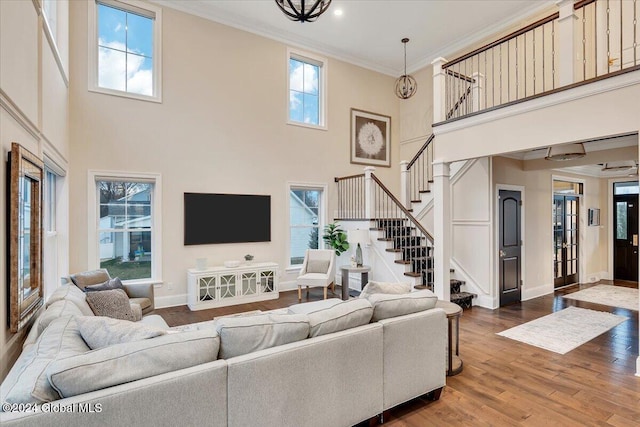 living room featuring stairway, a healthy amount of sunlight, wood finished floors, and ornamental molding