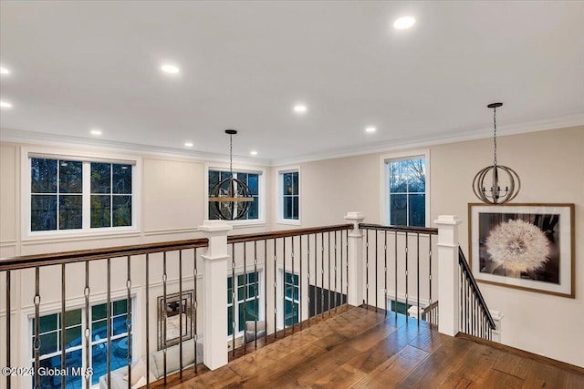 corridor with hardwood / wood-style floors, recessed lighting, crown molding, an upstairs landing, and a chandelier