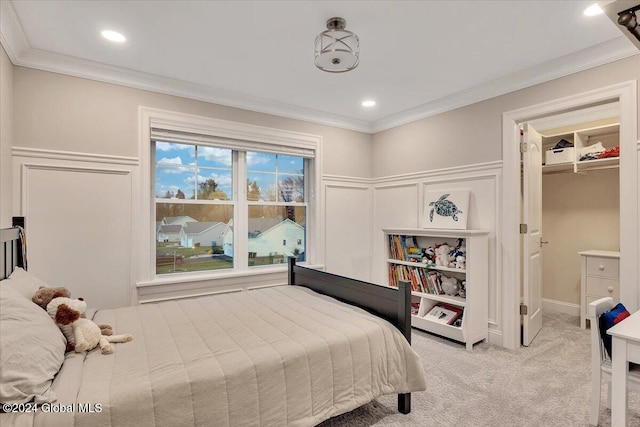 bedroom with recessed lighting, crown molding, a decorative wall, light colored carpet, and a spacious closet