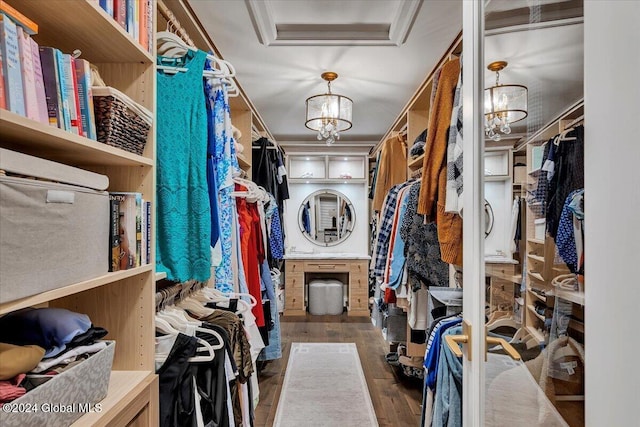 walk in closet with a notable chandelier and wood finished floors