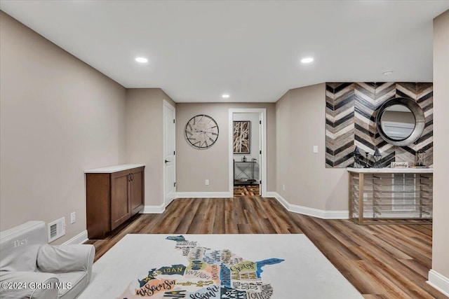 living room with recessed lighting, visible vents, baseboards, and wood finished floors