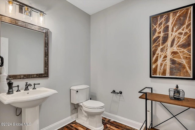 bathroom with a sink, toilet, baseboards, and wood finished floors