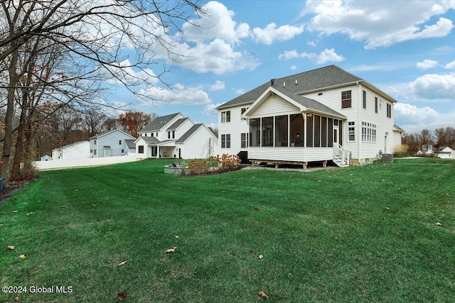 rear view of property featuring central AC unit, a yard, and a sunroom