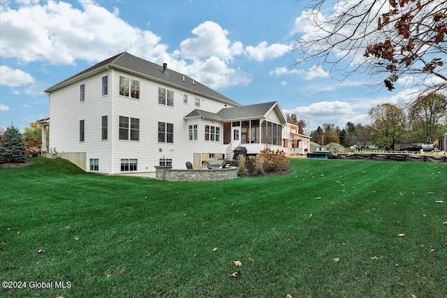 rear view of house with a patio, a lawn, and a sunroom