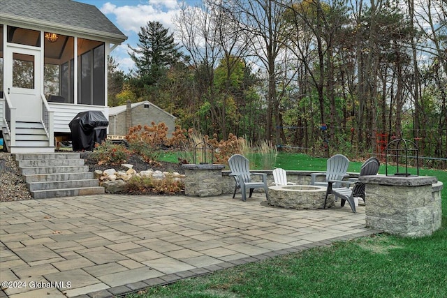 view of patio featuring area for grilling, a sunroom, and an outdoor fire pit