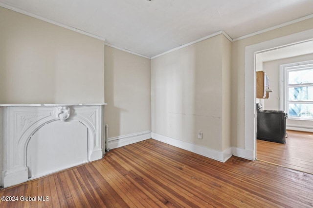 unfurnished living room featuring ornamental molding, a baseboard heating unit, and hardwood / wood-style flooring