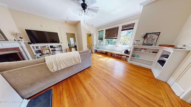 living room with a brick fireplace, ceiling fan, hardwood / wood-style floors, and crown molding