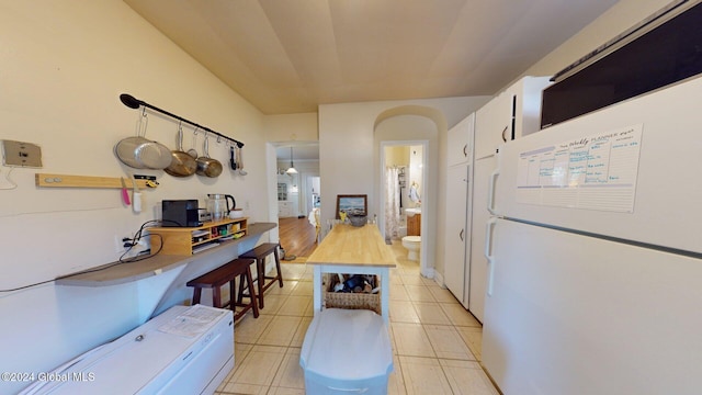 kitchen featuring white cabinets, white refrigerator, butcher block countertops, and decorative light fixtures