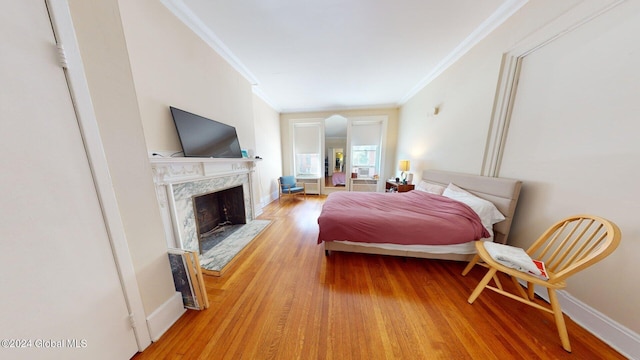 bedroom featuring wood-type flooring, a fireplace, and ornamental molding