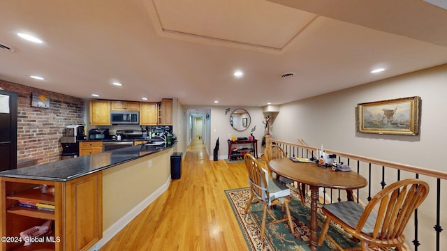 kitchen featuring brick wall, stainless steel appliances, and light wood-type flooring