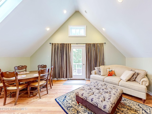 living room with vaulted ceiling with skylight and light wood-type flooring