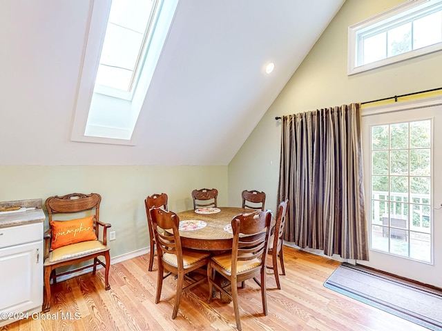 dining area with lofted ceiling with skylight, a wealth of natural light, and light hardwood / wood-style flooring