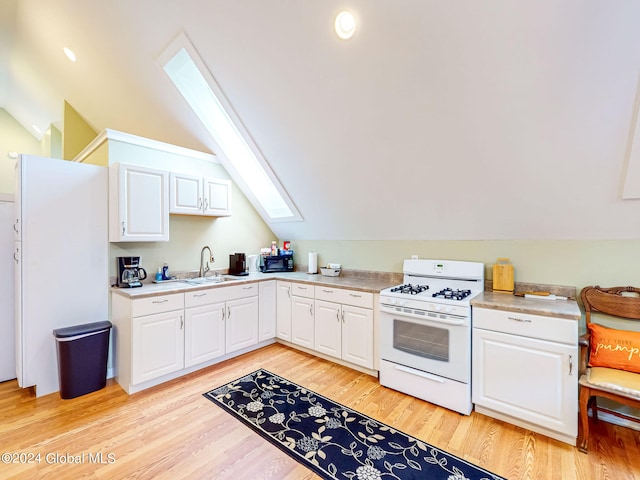 kitchen featuring white cabinetry, light hardwood / wood-style floors, white gas range, and lofted ceiling with skylight