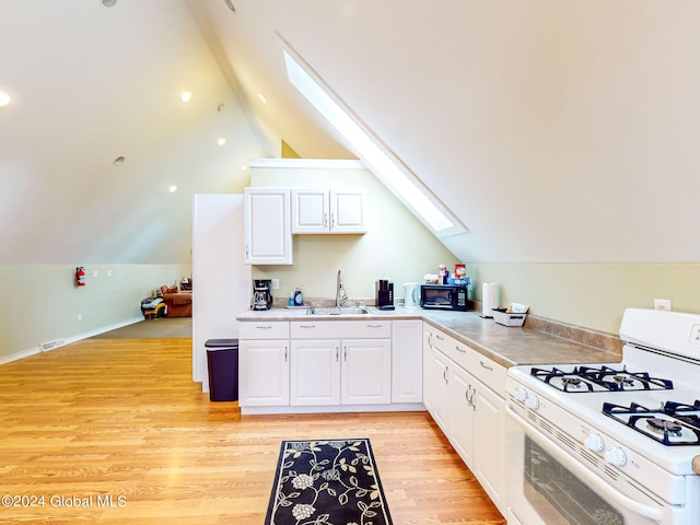 kitchen with white gas range, sink, light hardwood / wood-style floors, white cabinetry, and vaulted ceiling with skylight