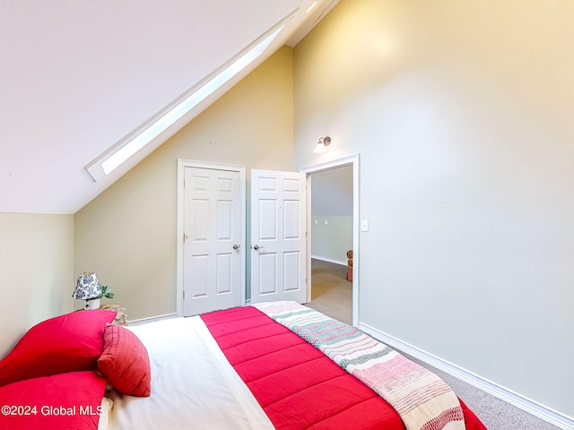 carpeted bedroom with vaulted ceiling with skylight