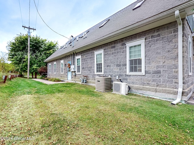 back of house with central AC and a lawn