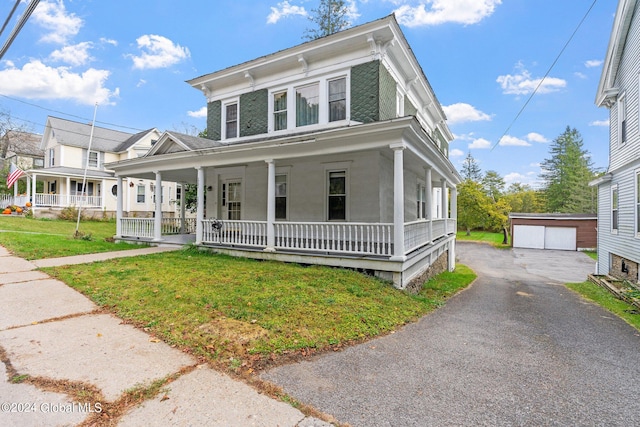 view of front of house with a front yard, an outdoor structure, a garage, and a porch