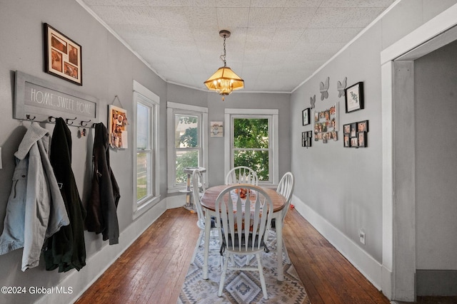 dining area with an inviting chandelier, ornamental molding, and dark hardwood / wood-style flooring