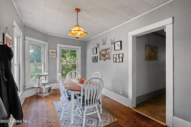 dining room with ornamental molding, an inviting chandelier, and dark hardwood / wood-style flooring