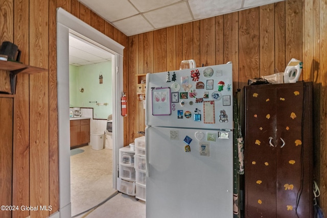 kitchen with carpet floors, wooden walls, a drop ceiling, and white fridge