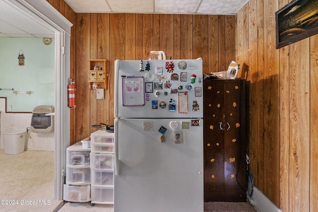 kitchen with carpet flooring, heating unit, wooden walls, and white fridge