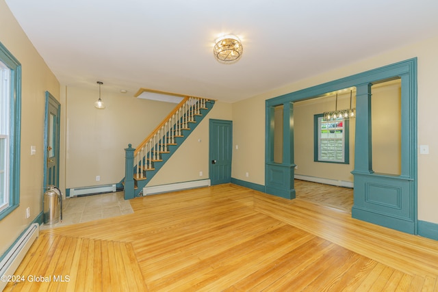 unfurnished living room with baseboard heating and hardwood / wood-style floors