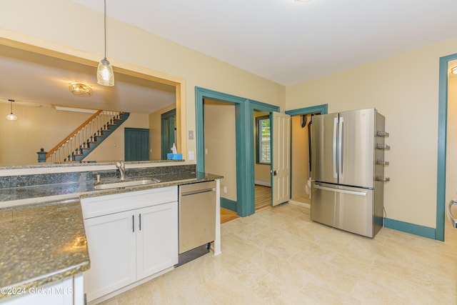 kitchen with dark stone counters, sink, white cabinets, appliances with stainless steel finishes, and decorative light fixtures