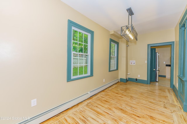 unfurnished room with an inviting chandelier, a baseboard heating unit, and light wood-type flooring