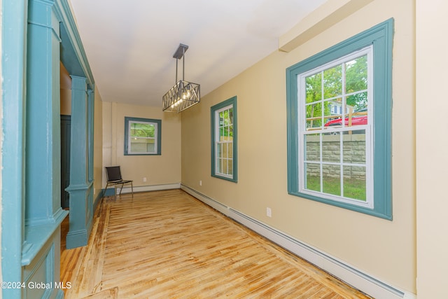 interior space with a notable chandelier, a baseboard radiator, and light hardwood / wood-style floors