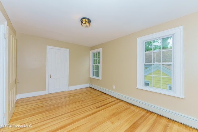 empty room with hardwood / wood-style floors and a baseboard heating unit