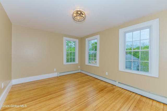 empty room with a baseboard radiator and light hardwood / wood-style floors