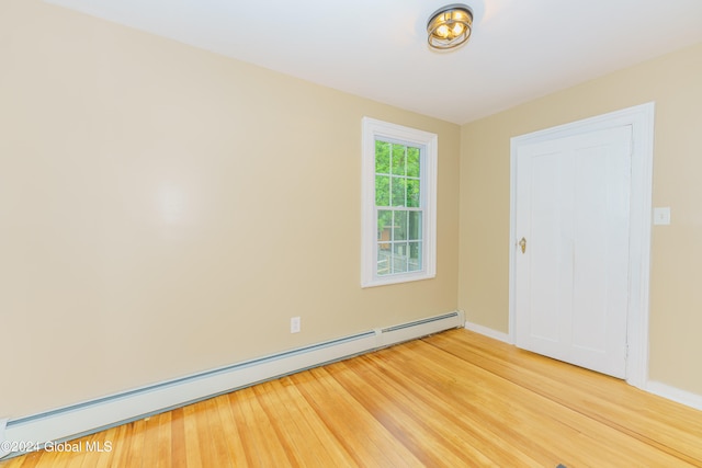 spare room featuring wood-type flooring and baseboard heating