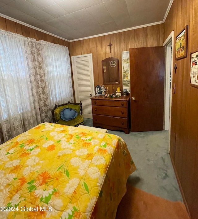 bedroom with wooden walls, crown molding, carpet floors, and a closet