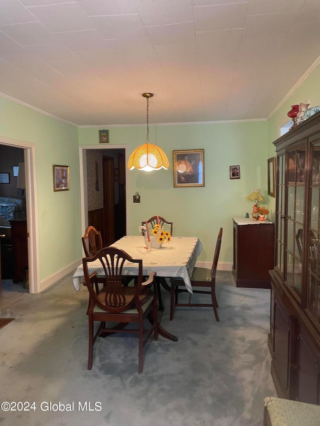 dining area with crown molding and dark colored carpet