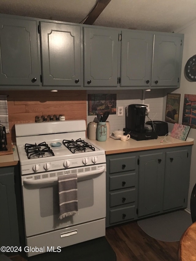 kitchen with gray cabinetry, decorative backsplash, white gas stove, and dark hardwood / wood-style flooring